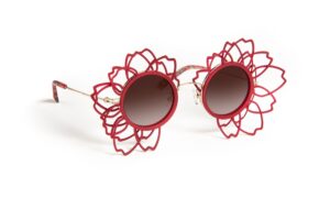 Vue de trois-quarts des lunettes de soleil J.F. REY SAKURA, soulignant la structure sculpturale rouge imprimée en 3D en forme de fleur de cerisier et les verres polarisés dégradés marron.