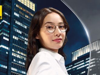 Nikon promotional poster for Z Series Single Vision lenses, featuring a woman with stylish eyeglasses reaching out against a illuminated city skyscraper backdrop, with the headline "EXPERIENCE LIFE WITH HIGHER DEFINITION: A NEW ERA OF SINGLE VISION LENSES."