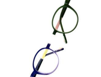 Top-down close-up of two round TREE Spectacles eyewear frames in green and blue, highlighting subtle graphic details and wave accents on the temple tips.