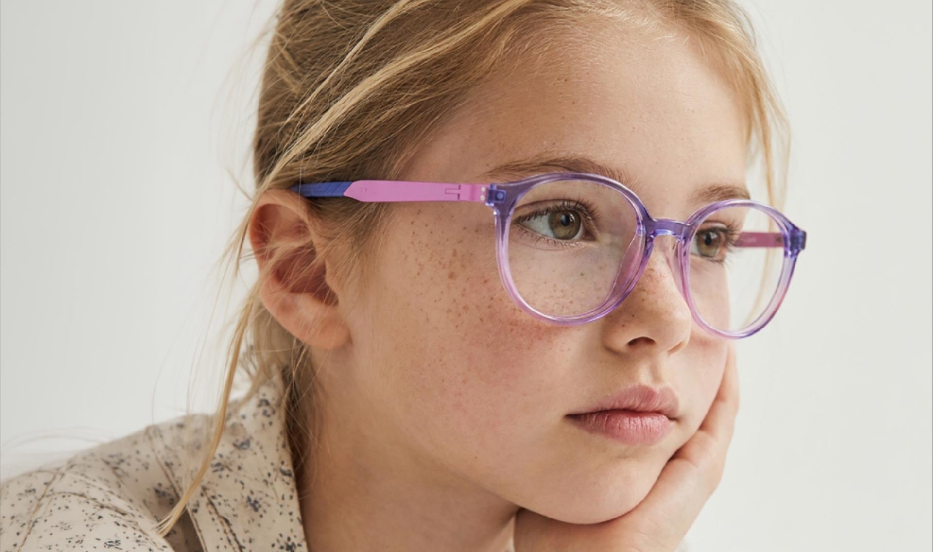 Young girl wearing LOOKKINO Nil 3950 translucent purple round prescription eyeglasses with pink temples for kids.