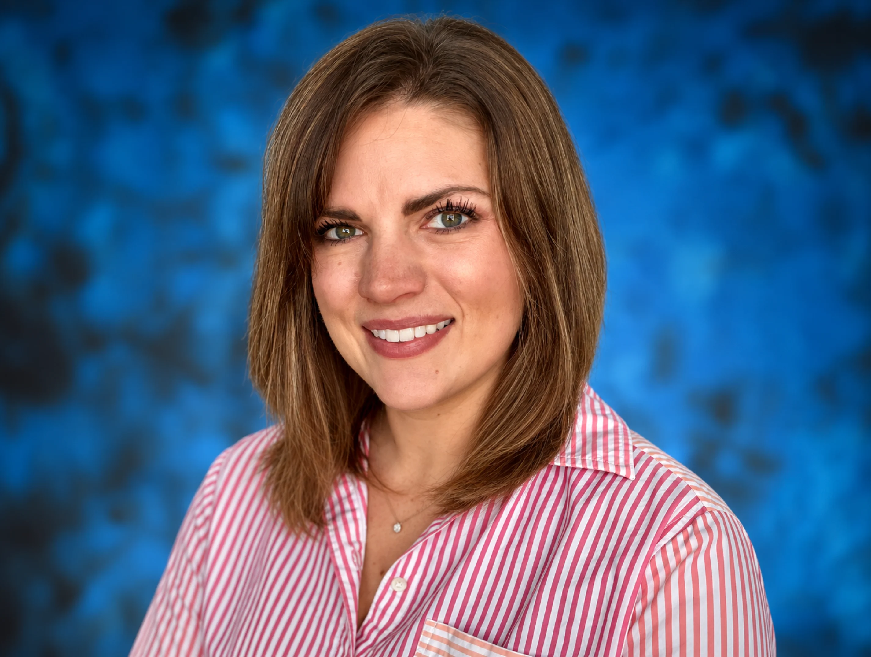 Kellie Wesley, directrice nationale des ventes ECP chez HOYA Vision Care, portrait professionnel sur fond bleu.