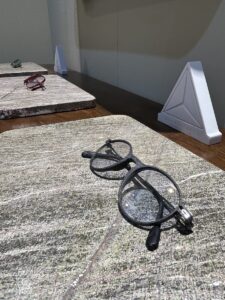 Alt text: Light MONTESTELLA bio-based carbon fiber optical frames displayed on a natural stone exhibit surface.