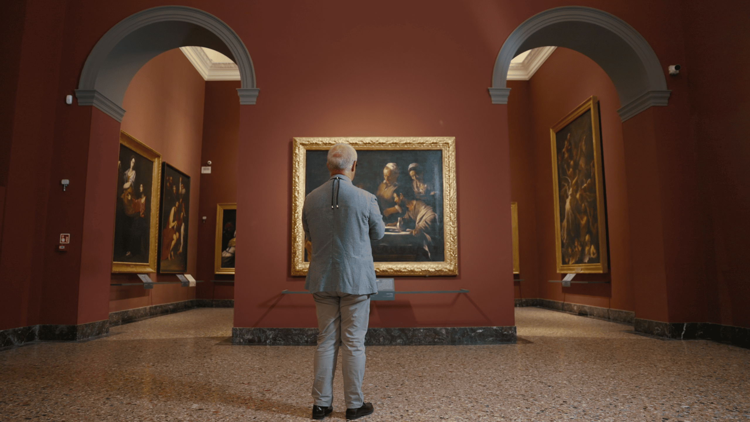 A visitor wearing Meta smart glasses stands in front of a painting at Pinacoteca di Brera during the Sensing Art accessibility project