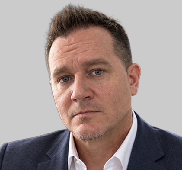 Portrait rapproché de Mike Sullivan, cadre responsable des comptes entreprises chez Ocuco, portant une veste de costume sombre et une chemise blanche.