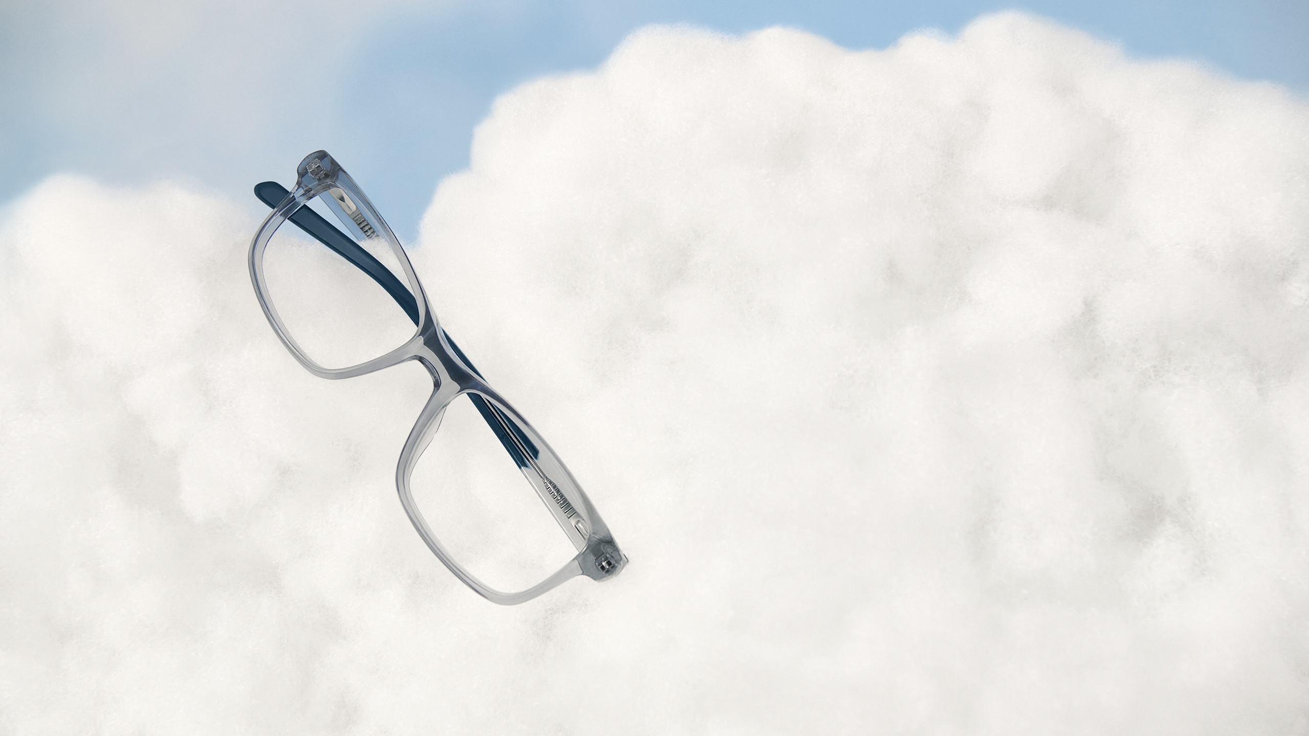 uperflex Kids SFK-343 crystal clear eyeglasses resting on white cloud-like background.